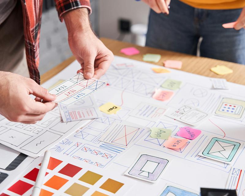 mehrere Personen stehen um ein Blatt Papier mit Post-its